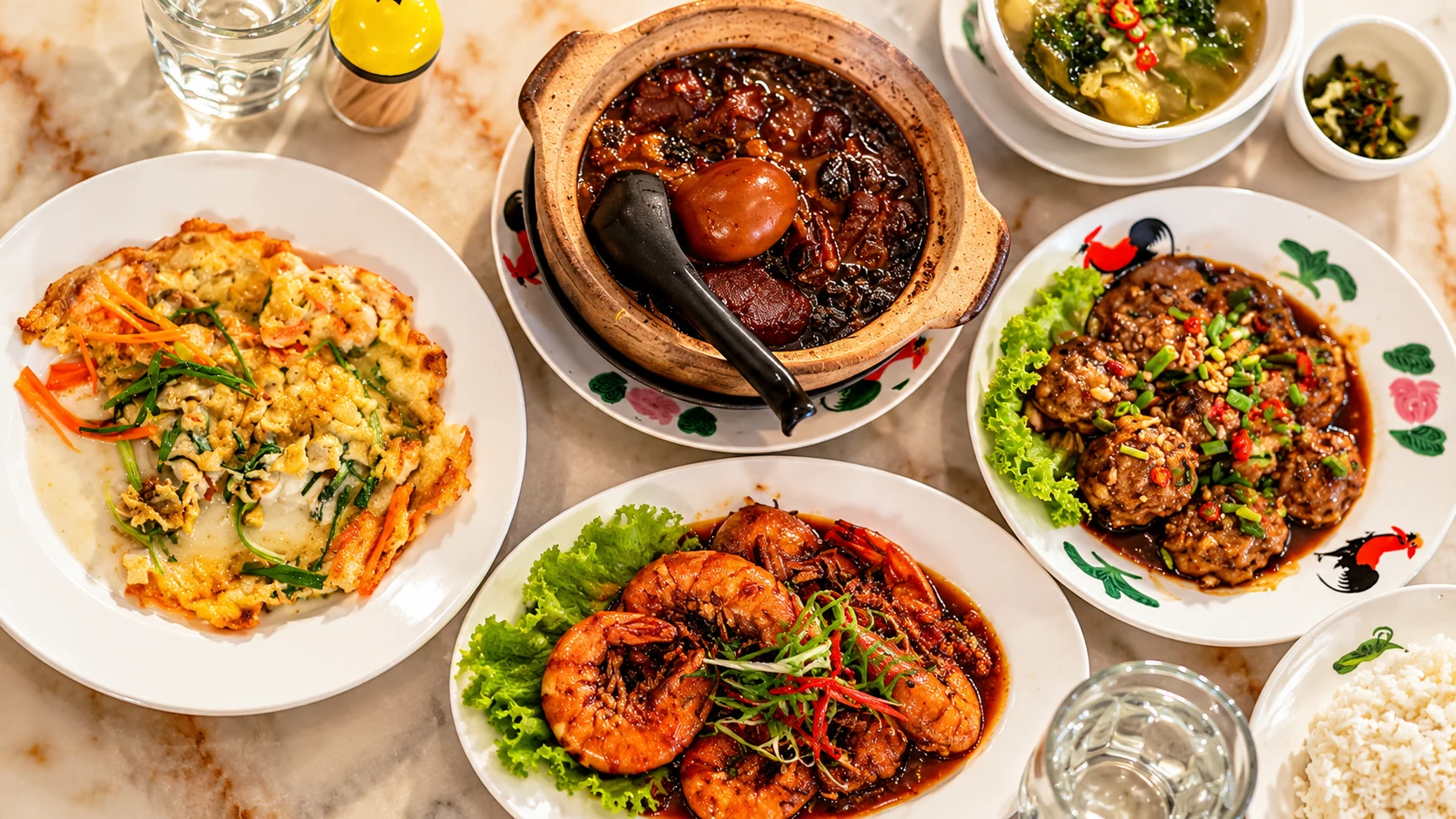 Overhead view of dishes, prawns, rice, bowls and clear glasses on a dining table.